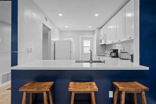 1400 NE 191st St Unit 307, Miami, FL 33179 - kitchen featuring white appliances, a sink, a peninsula, white cabinets, and recessed lighting