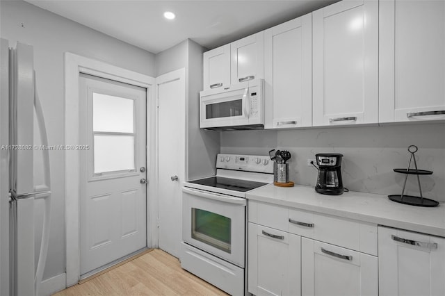 1400 NE 191st St Unit 307, Miami, FL 33179 - kitchen featuring white appliances, white cabinets, light wood-style flooring, light stone countertops, and recessed lighting