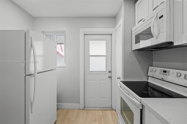 1400 NE 191st St Unit 307, Miami, FL 33179 - kitchen with white appliances, light wood-style flooring, light countertops, white cabinets, and baseboards