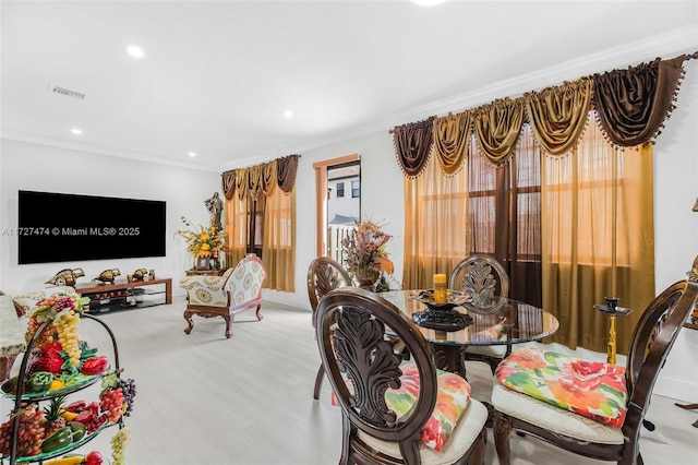 dining space featuring ornamental molding and light hardwood / wood-style floors