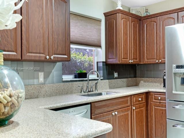 kitchen with light stone countertops, stainless steel appliances, backsplash, and sink