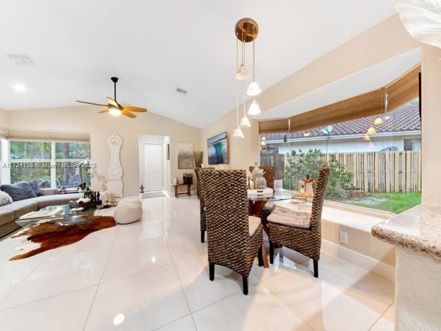 dining area with ceiling fan, light tile patterned floors, and vaulted ceiling