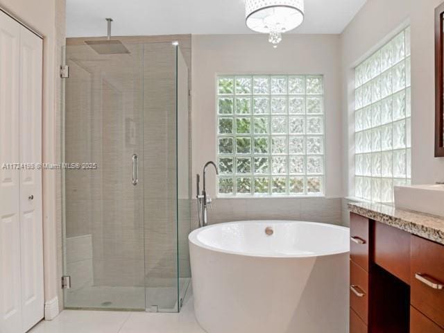 bathroom featuring independent shower and bath, tile patterned flooring, tile walls, and vanity