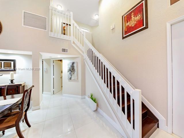 stairway featuring tile patterned flooring and a high ceiling