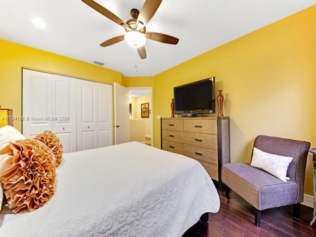 bedroom featuring ceiling fan, dark hardwood / wood-style floors, and a closet