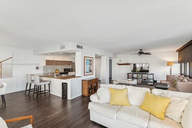 living room featuring ceiling fan and dark hardwood / wood-style flooring