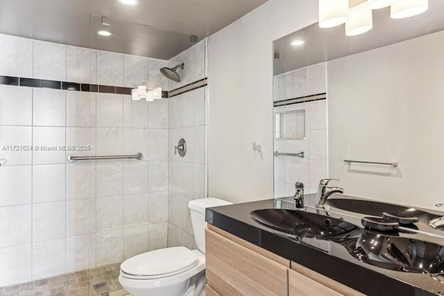 bathroom featuring toilet, tiled shower, and vanity