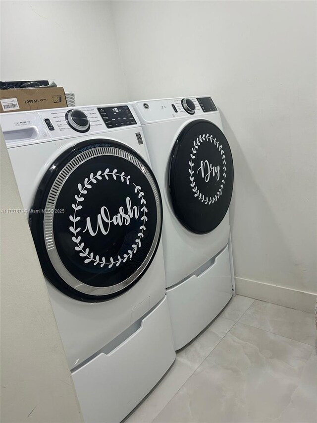 laundry area featuring light tile patterned floors and washing machine and clothes dryer