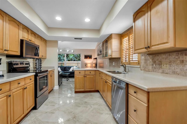 kitchen featuring stainless steel appliances, tasteful backsplash, sink, kitchen peninsula, and a tray ceiling