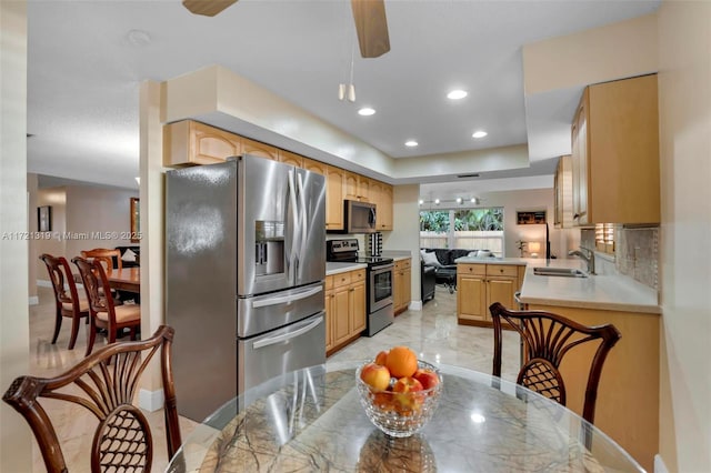 kitchen with sink, ceiling fan, kitchen peninsula, stainless steel appliances, and light brown cabinets