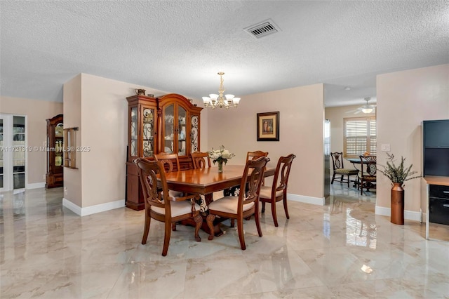 dining area with ceiling fan with notable chandelier and a textured ceiling