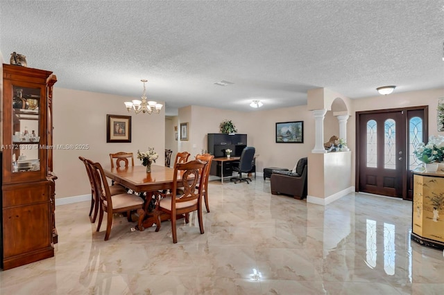 dining room featuring a notable chandelier, decorative columns, and a textured ceiling