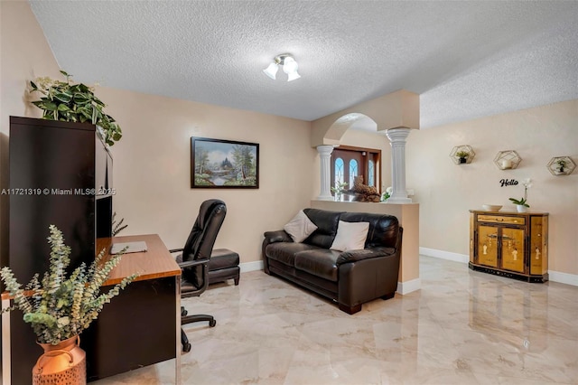 home office with a textured ceiling and decorative columns