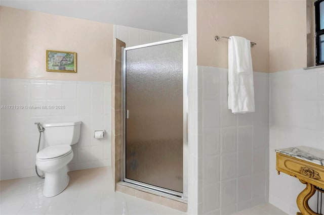 bathroom with tile walls, tile patterned flooring, a shower with door, and toilet