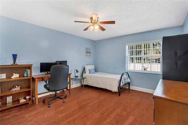 bedroom featuring ceiling fan, wood-type flooring, and a textured ceiling