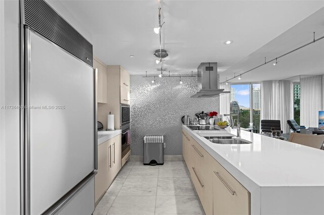 kitchen featuring sink, built in refrigerator, a center island, radiator, and island exhaust hood