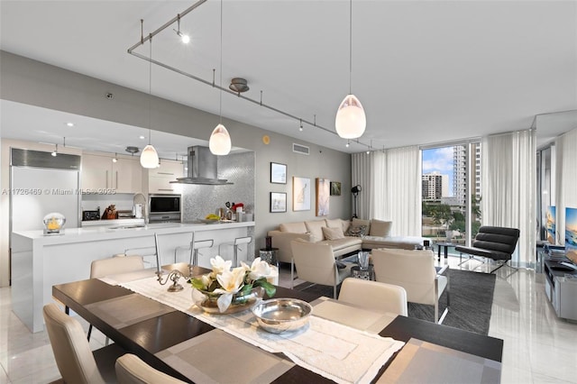 dining space featuring track lighting, floor to ceiling windows, sink, and light tile patterned floors