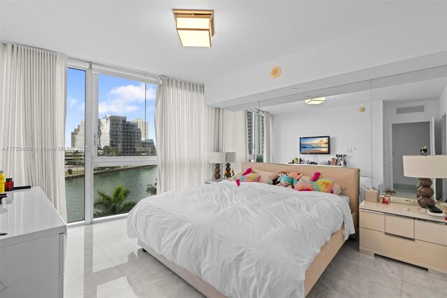 tiled bedroom featuring expansive windows, a water view, and access to exterior