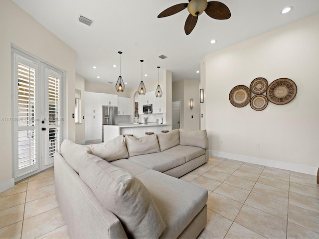 tiled living room with ceiling fan and french doors