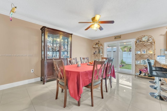 tiled dining room with ceiling fan, crown molding, and a textured ceiling