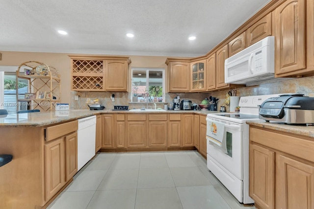 kitchen featuring sink, white appliances, light stone countertops, and tasteful backsplash