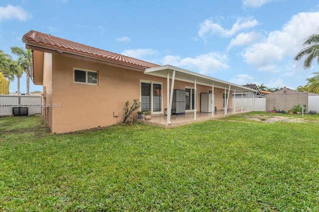 back of house featuring a patio area, a lawn, and a shed