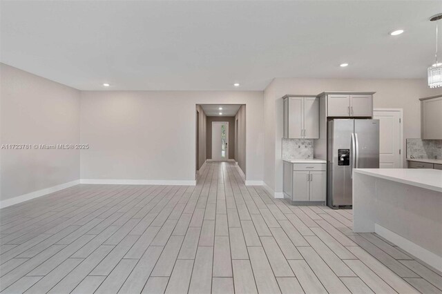 kitchen with gray cabinetry, decorative light fixtures, stainless steel fridge, and decorative backsplash