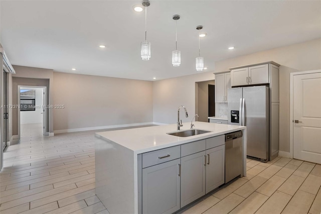 kitchen featuring sink, gray cabinetry, appliances with stainless steel finishes, an island with sink, and pendant lighting