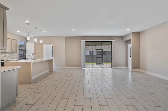 kitchen with sink, pendant lighting, light hardwood / wood-style floors, and decorative backsplash