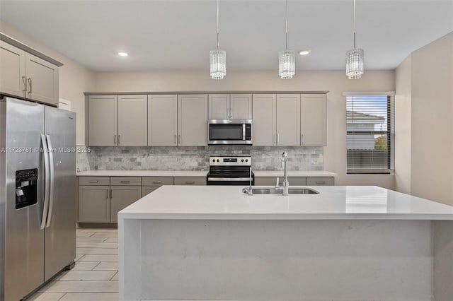 kitchen with stainless steel appliances, a kitchen island with sink, sink, and decorative light fixtures