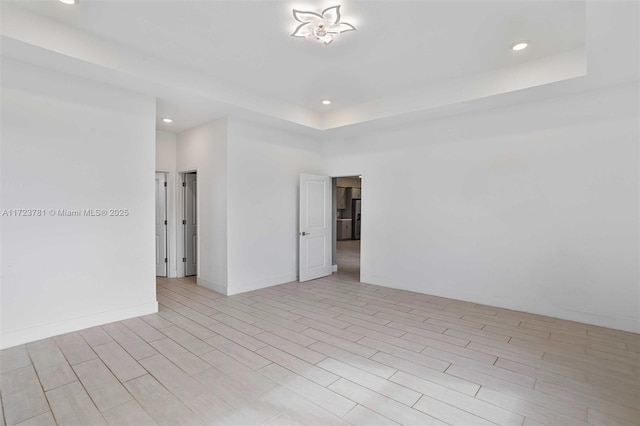 unfurnished room with a tray ceiling and light hardwood / wood-style flooring