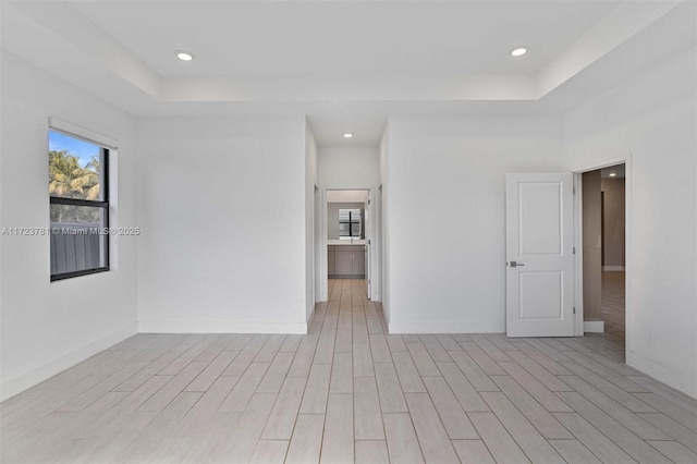 unfurnished room featuring a tray ceiling and light hardwood / wood-style flooring