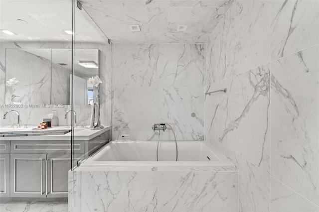 bathroom with vanity and tiled tub