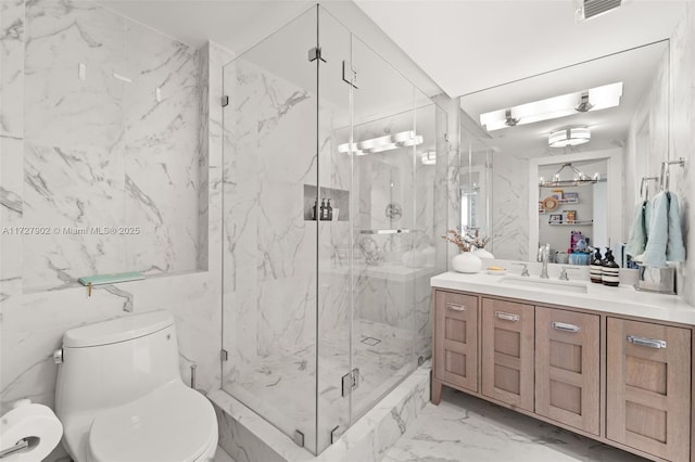 bathroom featuring a shower with door, vanity, and toilet