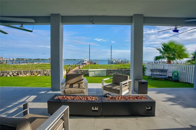 view of patio with a trampoline, a water view, and a fire pit