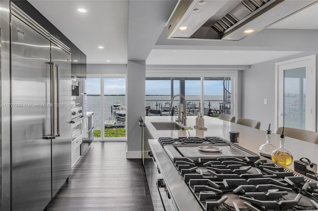 kitchen featuring a water view, a healthy amount of sunlight, stainless steel built in fridge, and sink