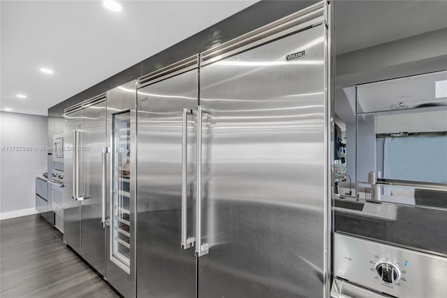 kitchen with dark hardwood / wood-style floors, stainless steel built in fridge, and oven