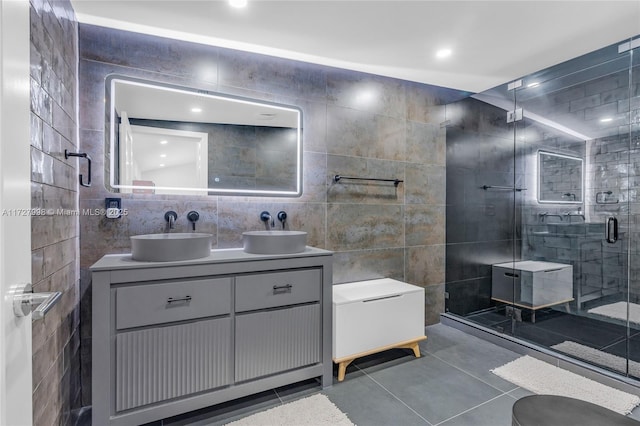 bathroom with a shower with shower door, tile walls, tile patterned floors, and vanity