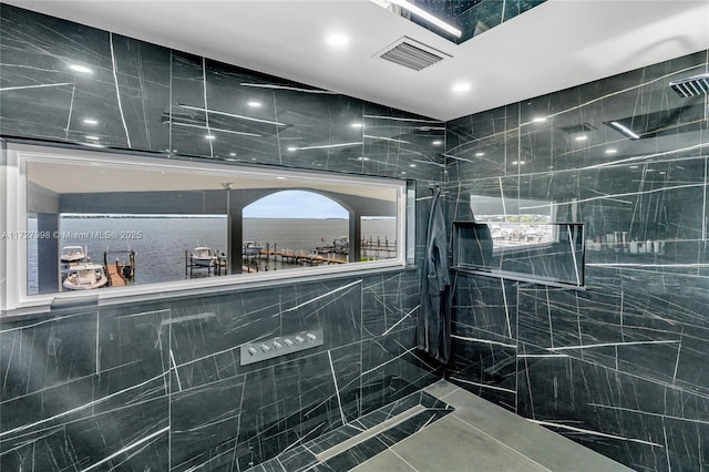 bathroom featuring tile walls, walk in shower, and a water view