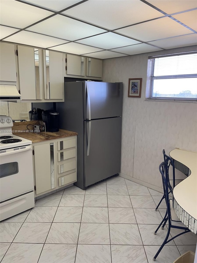 kitchen with white electric range oven, custom exhaust hood, tasteful backsplash, stainless steel fridge, and cream cabinets