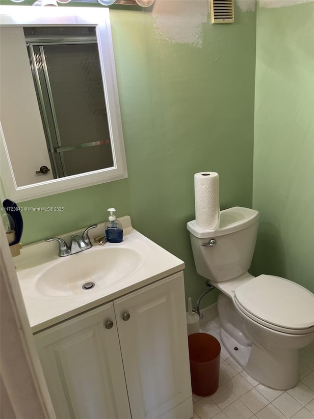 bathroom with toilet, vanity, and tile patterned flooring