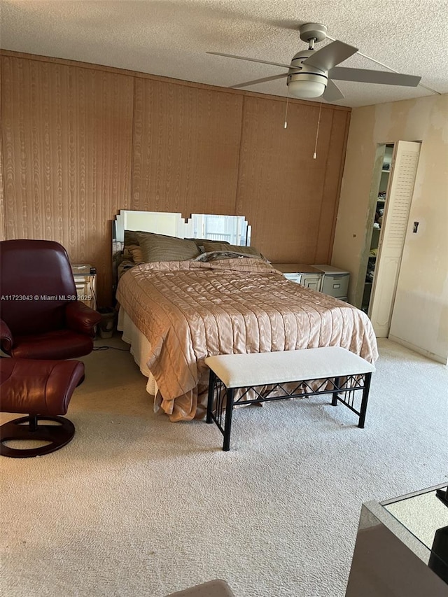 bedroom with ceiling fan, a textured ceiling, wood walls, and carpet flooring