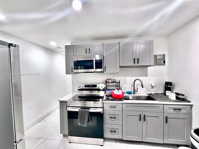 kitchen with appliances with stainless steel finishes, sink, and gray cabinetry