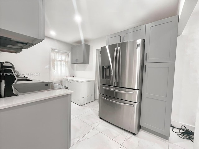 kitchen with gray cabinets, light stone counters, stainless steel fridge with ice dispenser, and refrigerator