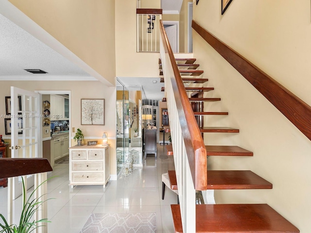 stairway featuring a textured ceiling, ornamental molding, and tile patterned flooring