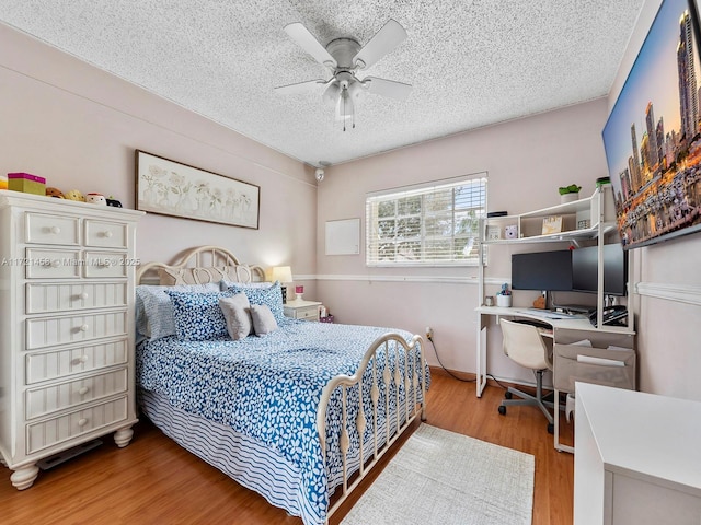 bedroom with ceiling fan, a textured ceiling, and hardwood / wood-style flooring