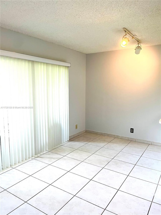 empty room with a textured ceiling and light tile patterned floors