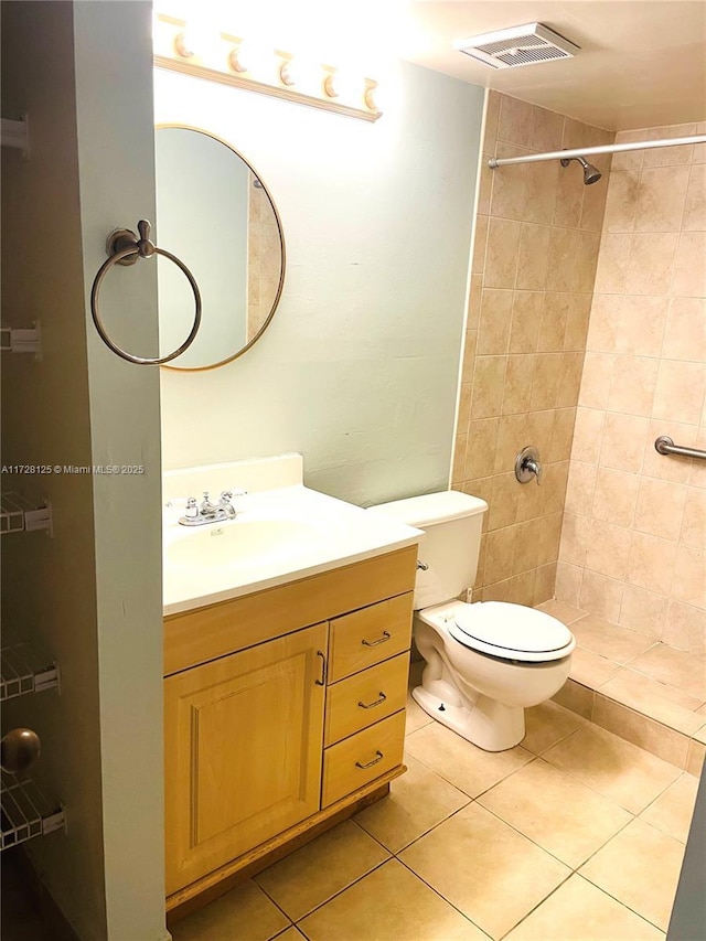 bathroom featuring toilet, a tile shower, tile patterned floors, and vanity