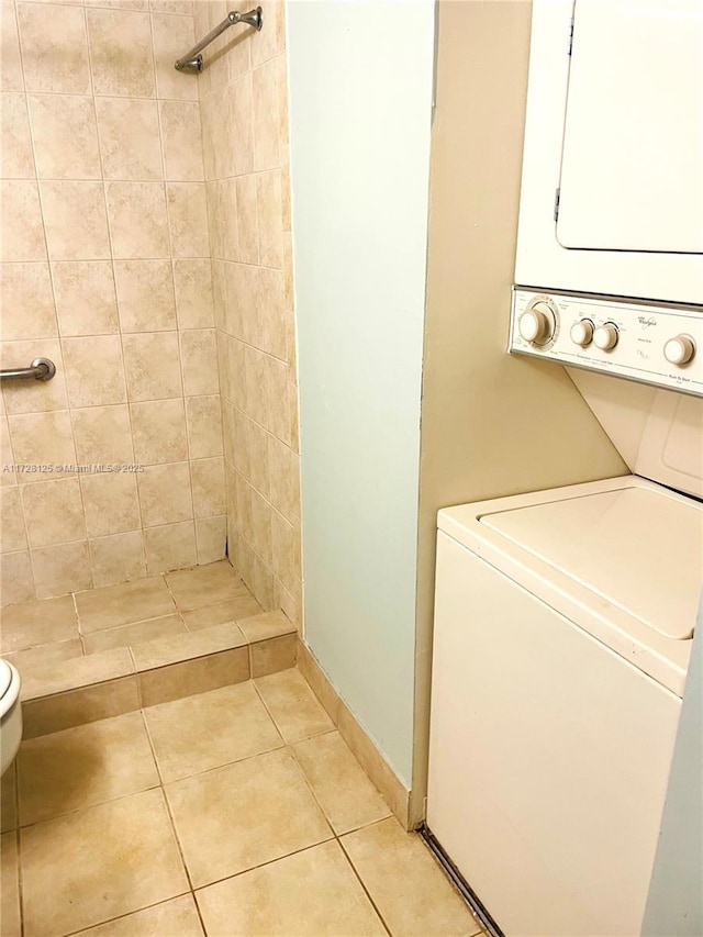 bathroom featuring tile patterned floors, stacked washer / drying machine, tiled shower, and toilet