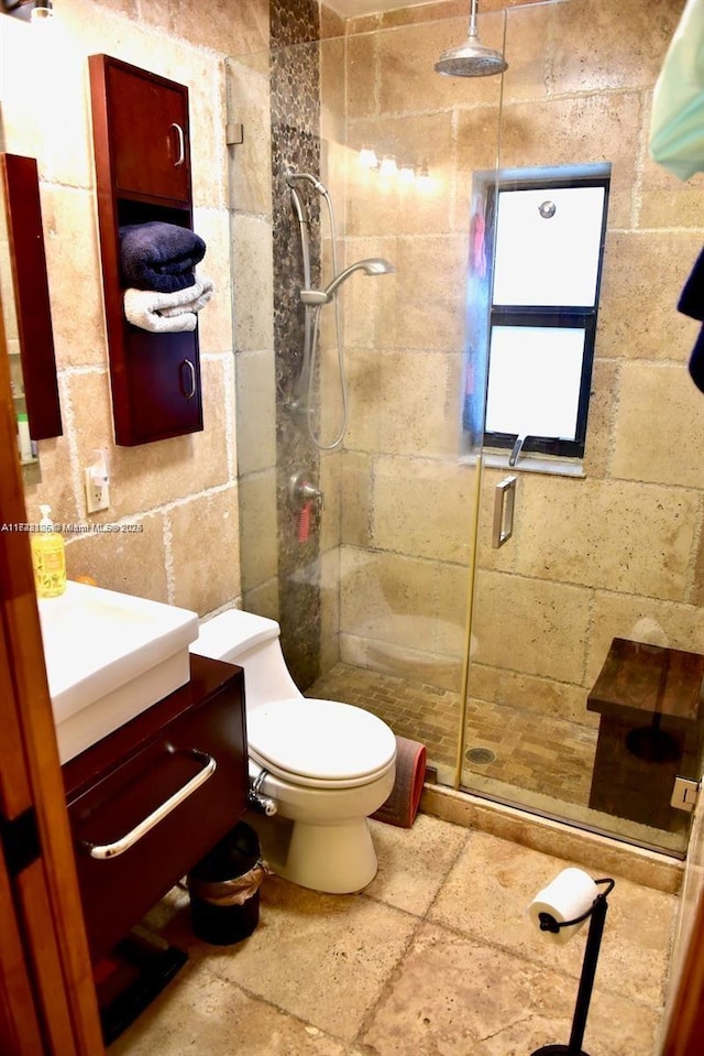 bathroom featuring an enclosed shower, vanity, tile walls, and toilet